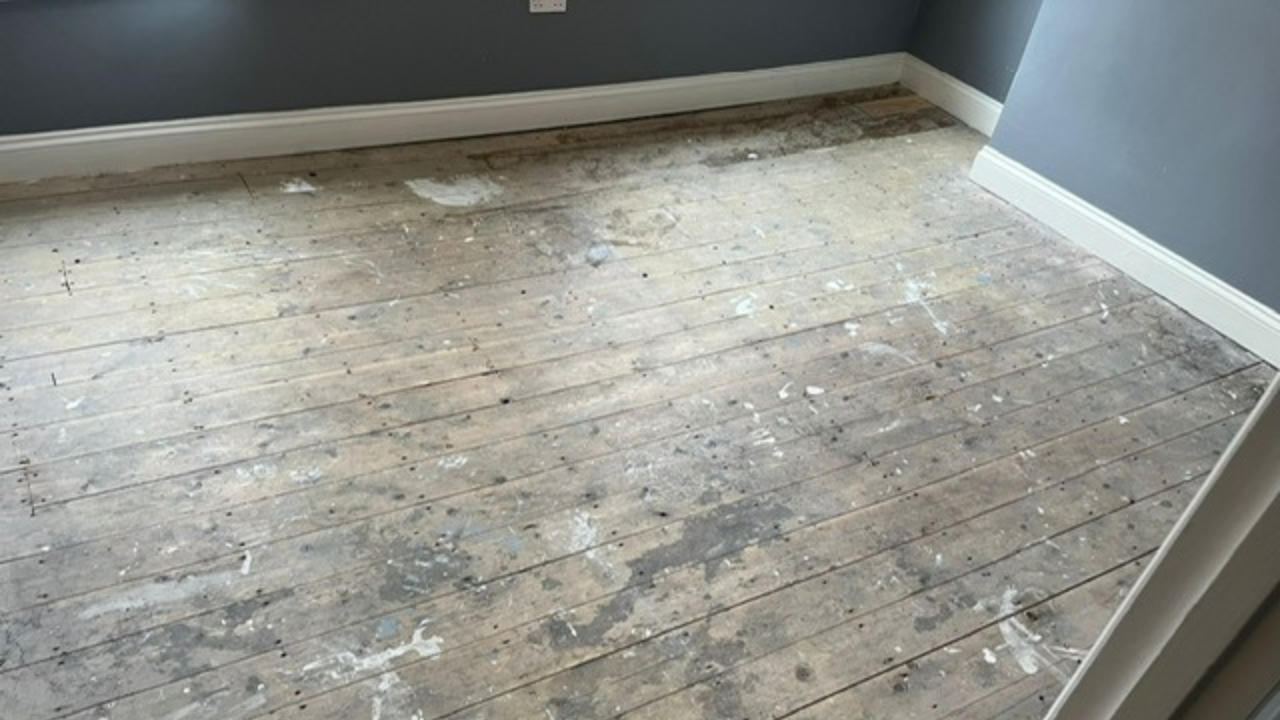 Wood Floor Sanding in south-west-london — bedroom with worn Victorian softwood pine floorboards covered in paint splashes and grey traffic marks, ready for restoration.
