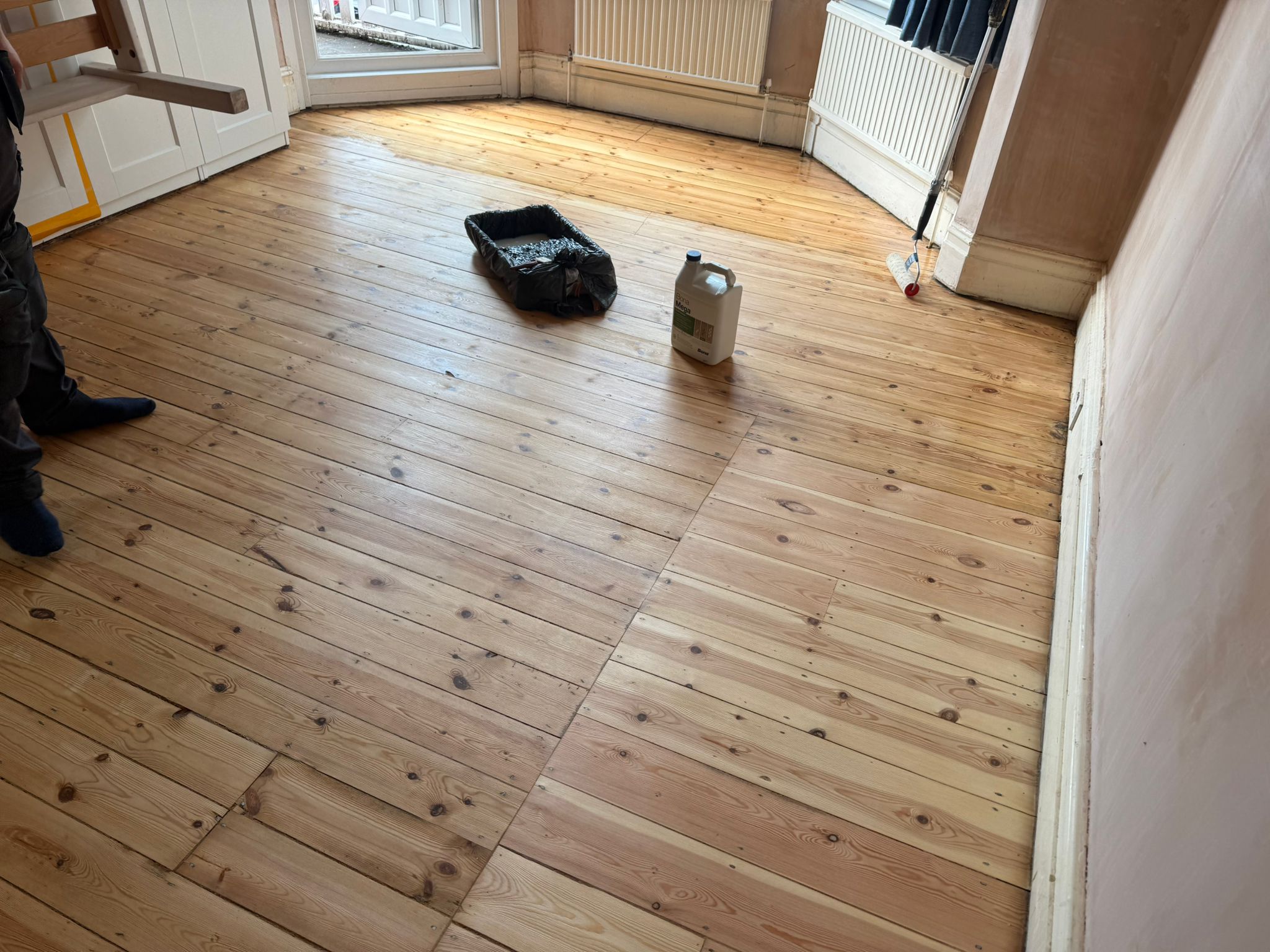 Wood Floor Sanding in south-west-london — Victorian softwood pine floorboards freshly sanded and ready for finishing, with roller tray and finish container in a bay-fronted room.