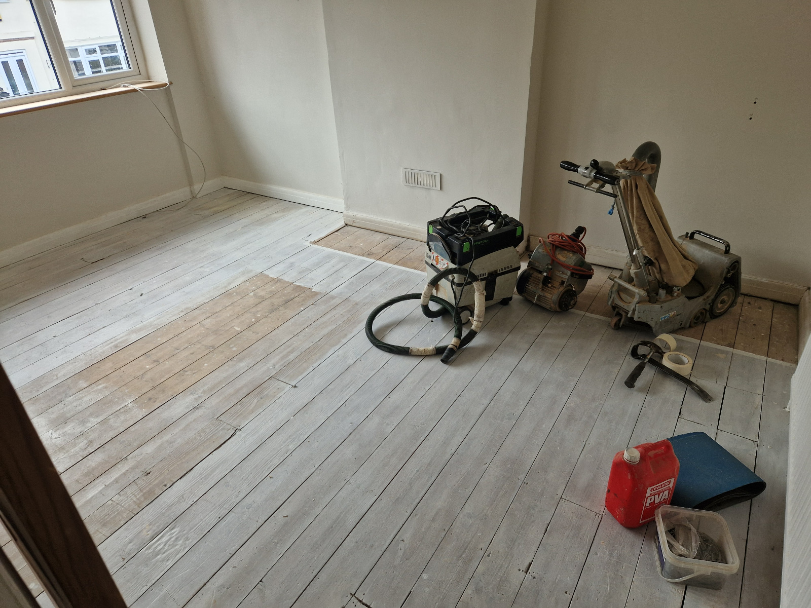 Wood Floor Sanding in south-west-london — dust-free preparation of Victorian softwood pine floorboards with belt sander, edge sander and HEPA extractor in a bright room.