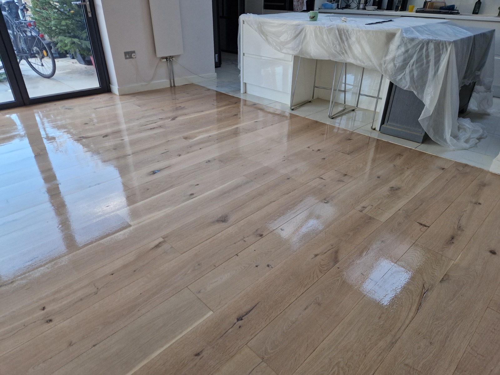 Hardwood Floor Refinishing in south-west-london – engineered oak plank kitchen-diner floor freshly coated with clear lacquer, showing a smooth, reflective like-new finish.