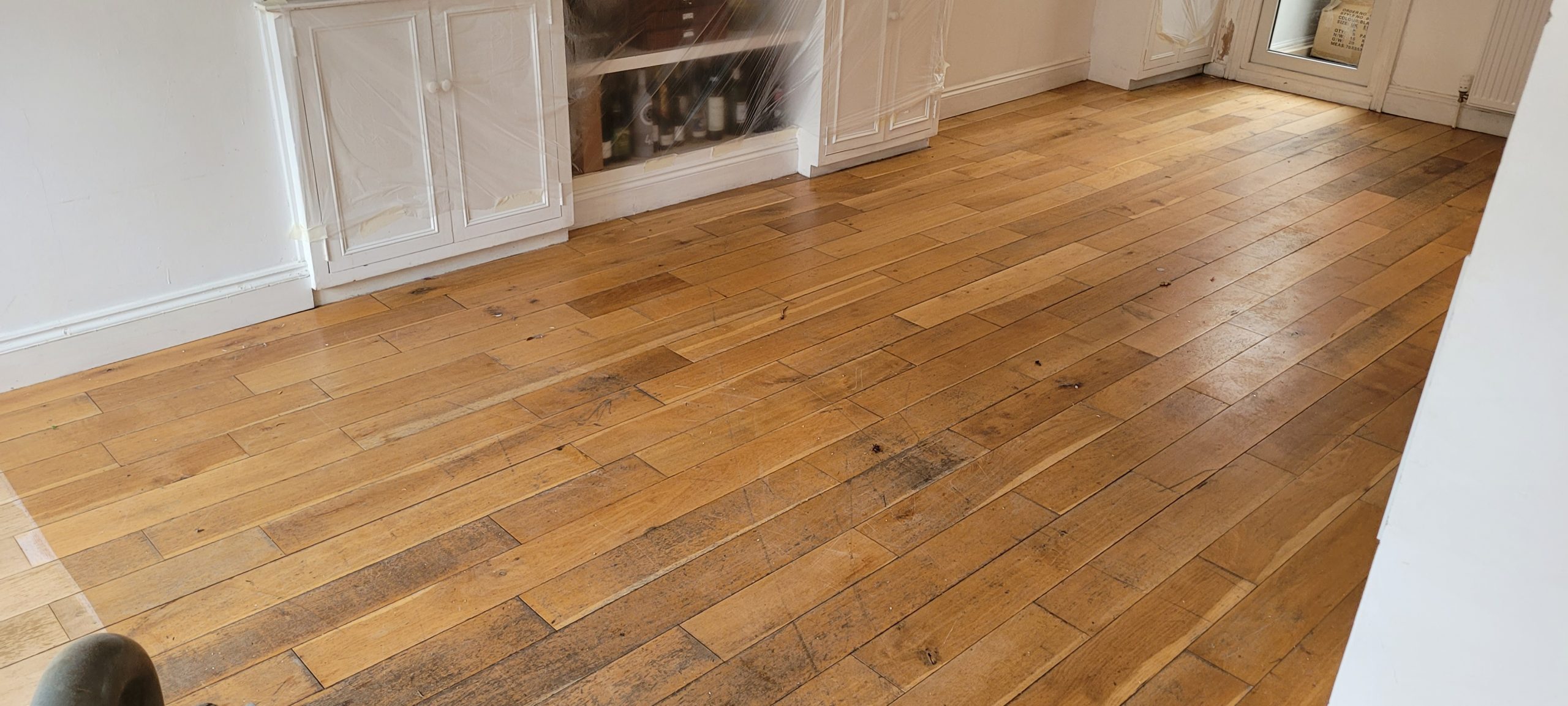 Hardwood Floor Refinishing in south-west-london – engineered oak plank hardwood dining room floor showing worn, scratched and stained boards before professional sanding and sealing.