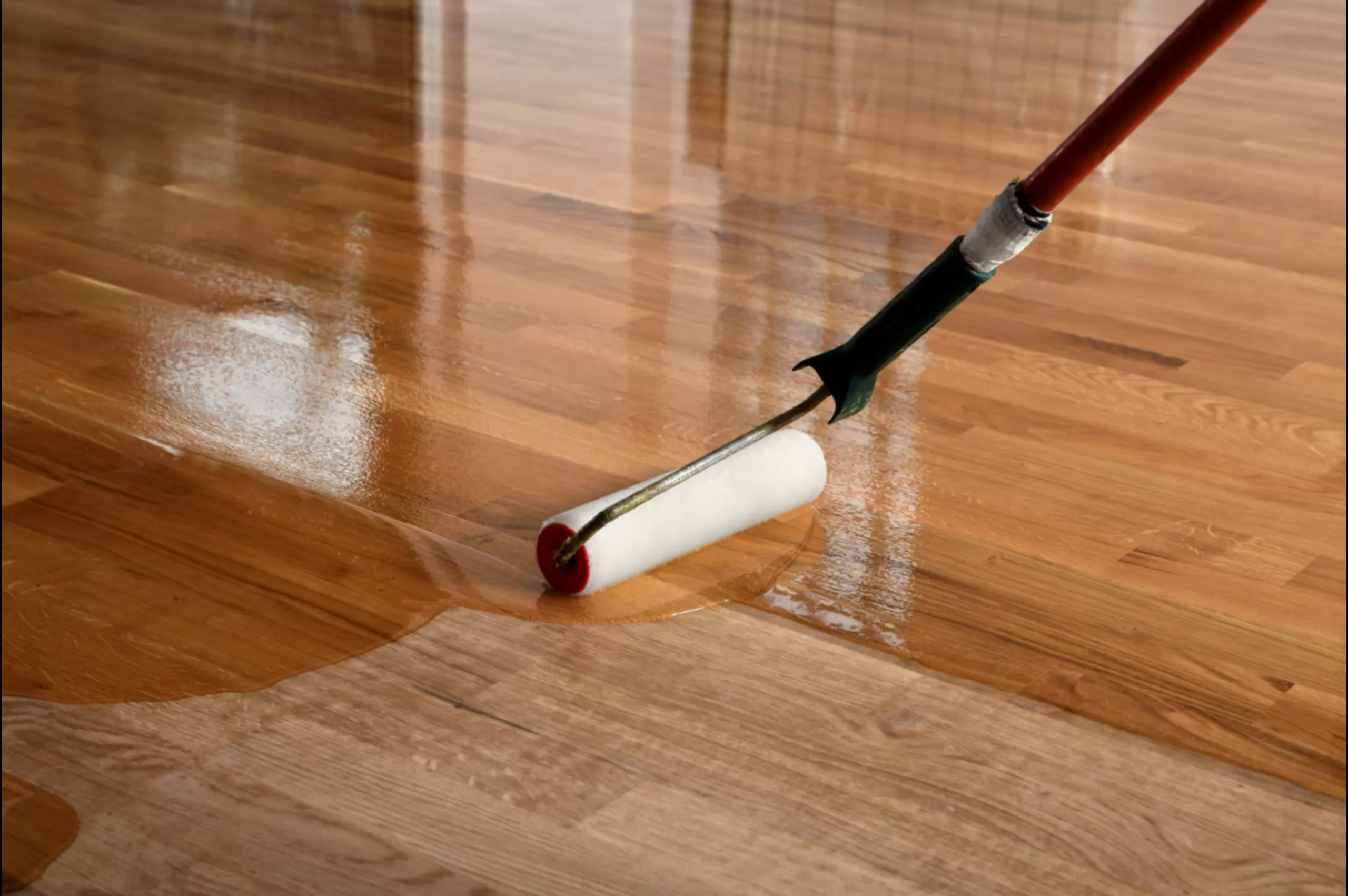 Hardwood Floor Refinishing South-West-London | Solid Oak Plank Lacquer Finish Hardwood Floor Refinishing in south-west-london – solid oak plank hardwood floor being coated with clear lacquer using a roller, showing contrast between sanded wood and freshly sealed surface.