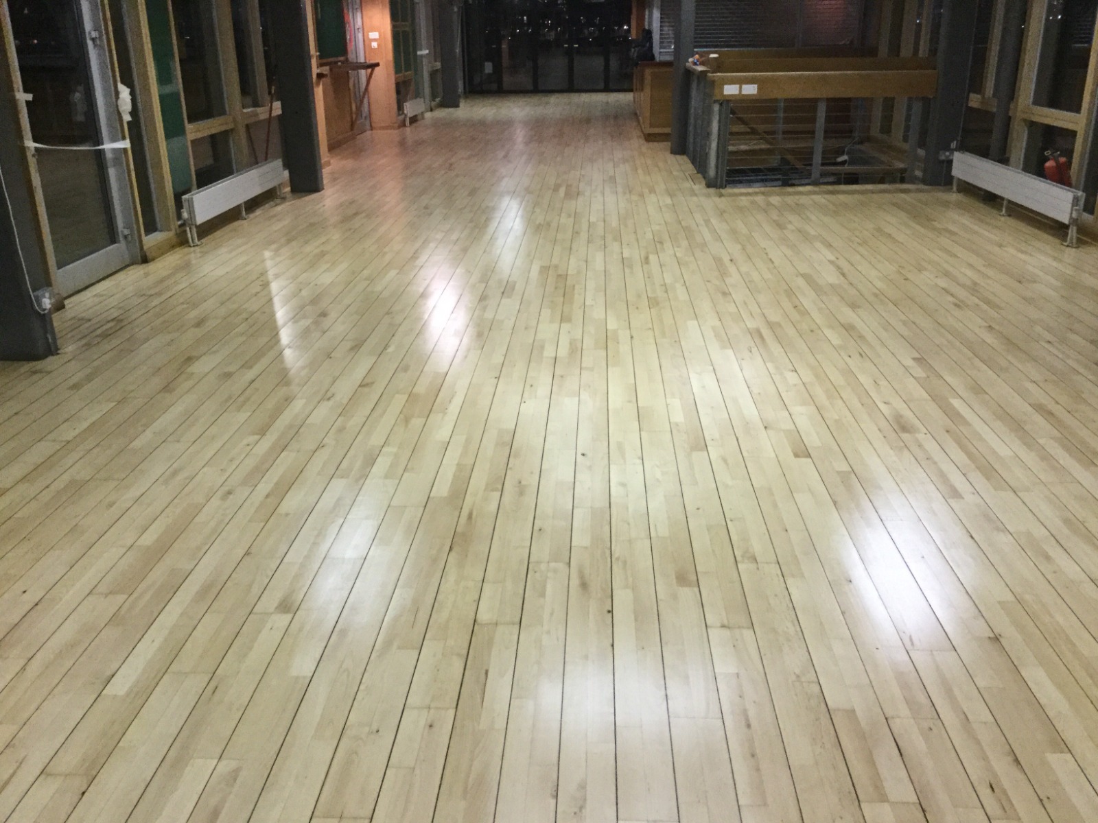Freshly sanded and sealed light oak wooden floor in a modern church community hall, showing a smooth high-gloss finish after professional dust-free floor sanding